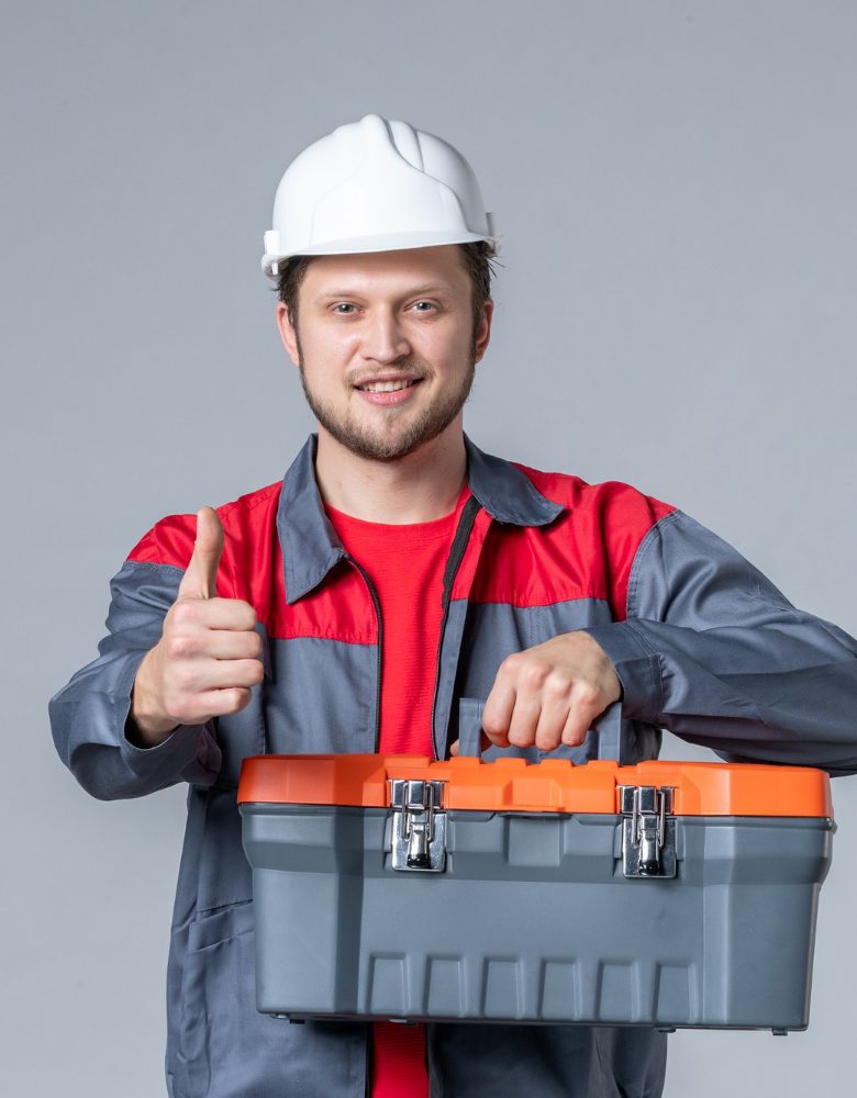 front-view-male-builder-uniform-helmet-holding-tool-case-gray-background